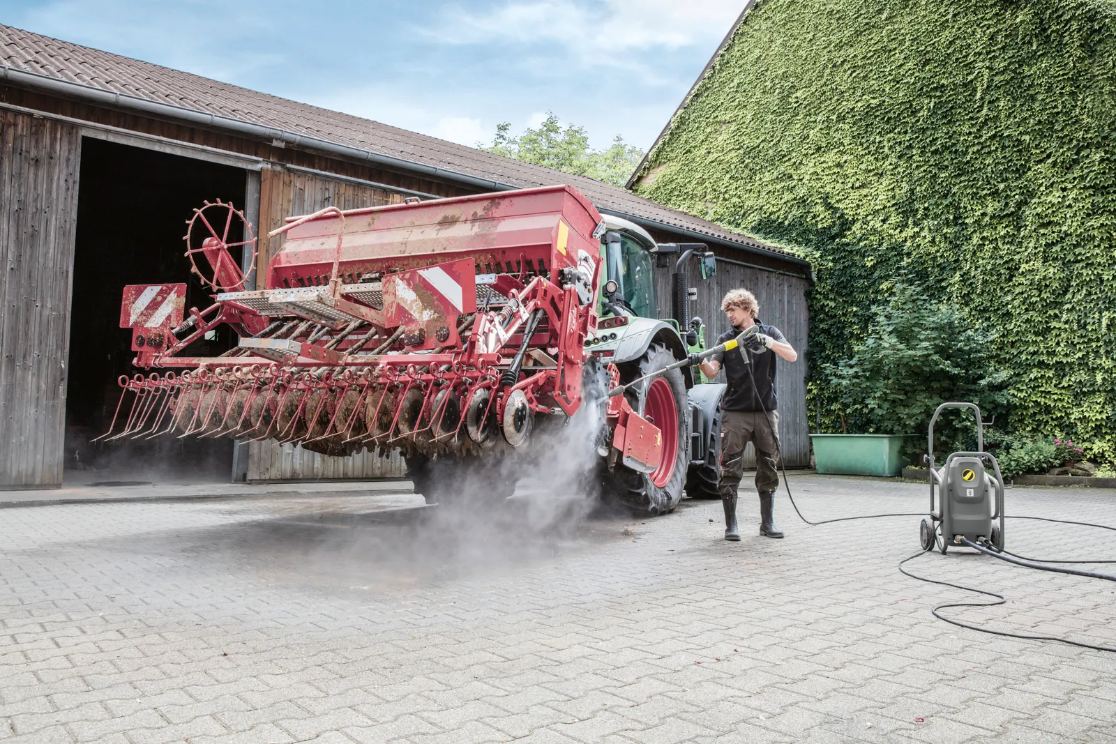 Kärcher Hochdruckreiniger beim Reinigen einer Sämaschine auf dem Hofplatz